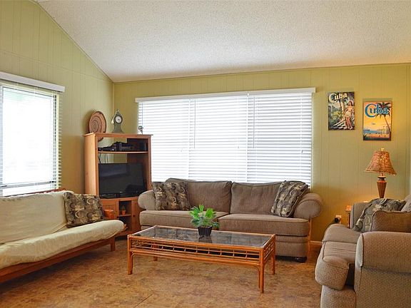 Enter through the sliding glass door to an inviting living/kitchen/dining concept that features high vaulted ceilings & well-maintained vinyl flooring.