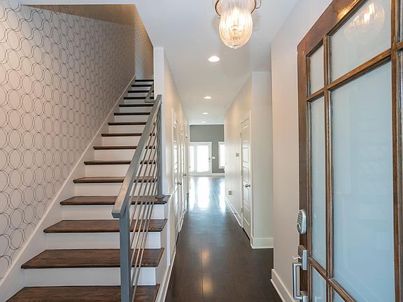 Entry foyer with glass-paneled front door and modern staircase.