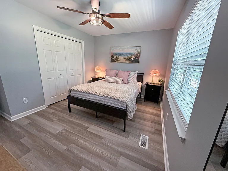 Queen bedroom 1 decorated in pink hues with plush linens, dresser and closet for clothing storage