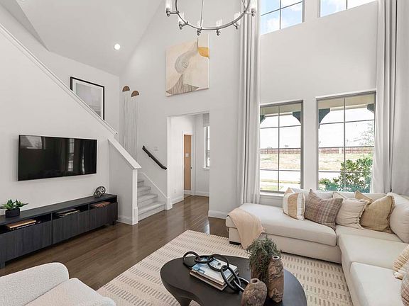 Open-concept family room featuring dramatic double-height ceilings, large windows, abundant natural