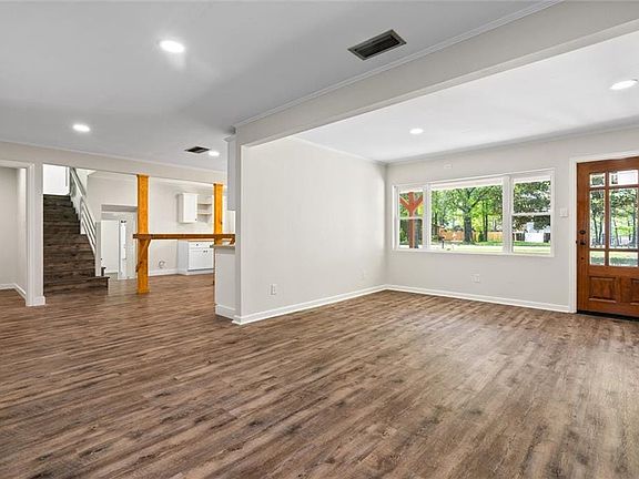 Unfurnished living room featuring baseboards, dark wood finished floors, and visible vents