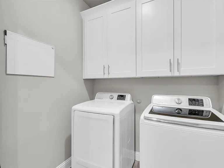 Utility room featuring white shaker-style cabinetry with brushed nickel hardware, and wood-finish flooring
