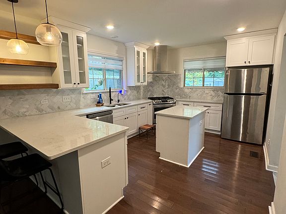 open kitchen with stainless steel appliances and gas stove, and quartz countertops.