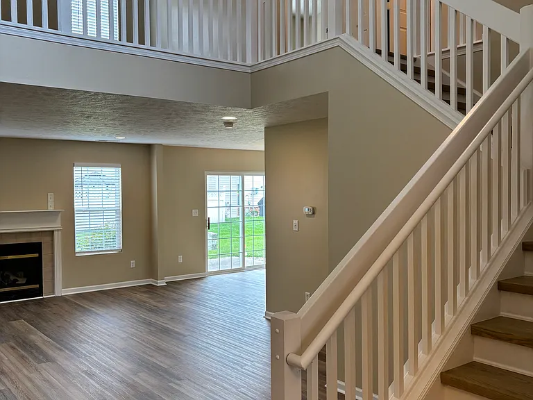 Two-story foyer with exposed stair case with new solid wood stair treads.