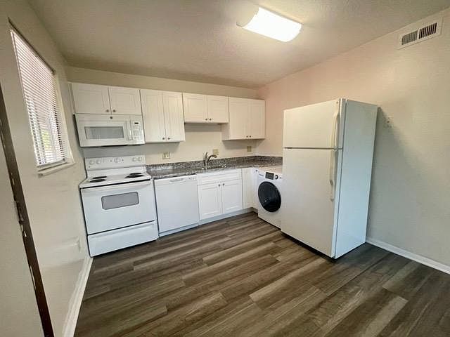 Kitchen, includes washer/dryer, dishwasher, microwave, lazy susan, upgraded white appliances, granite countertops, new faucet fixtures, garbage disposal, and window for natural lighting.