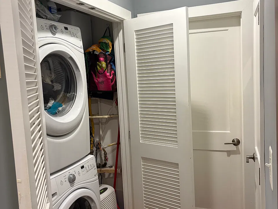 Hallway and other angle of in-unit washer-dryer + storage.