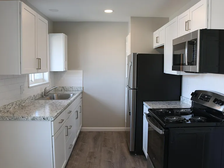 Kitchen includes new GE stainless steel appliances, white shaker cabinets with brushed nickel pulls and subway tile backsplash.