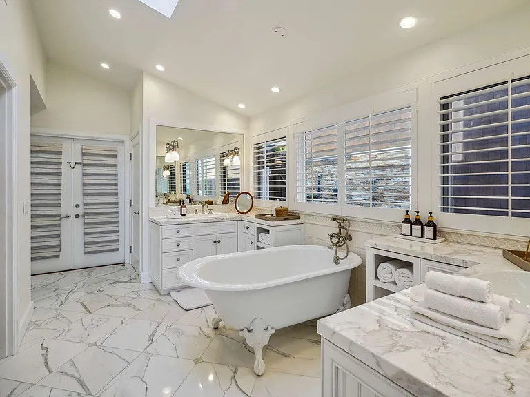 A freestanding clawfoot tub set against marble floors.