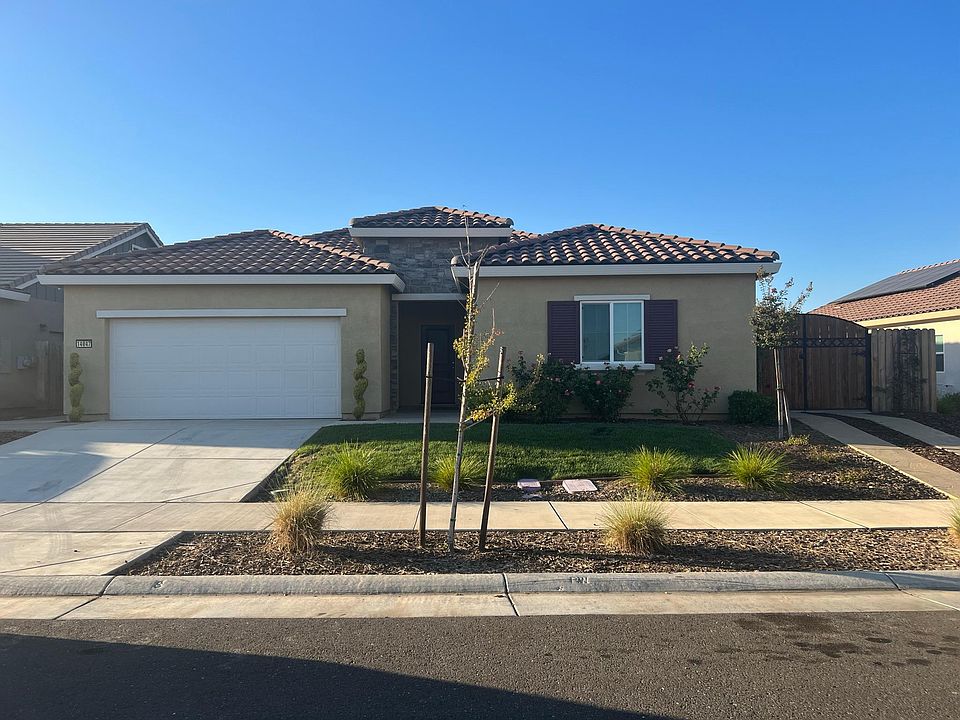 Front view of the home shows additional drive in front of gate leading to concrete parking behind gate in side yard.