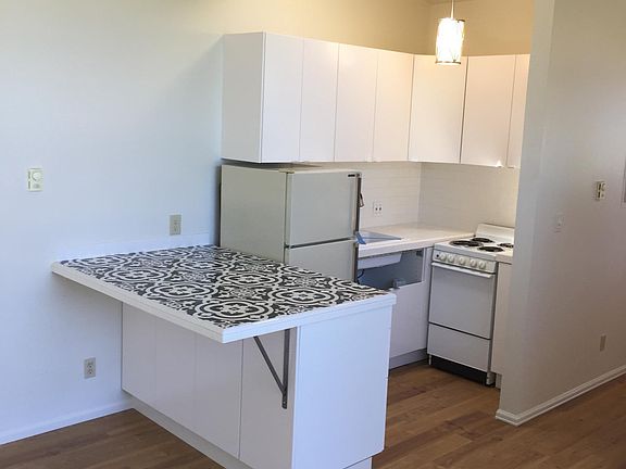 This is a like-layout unit. The available unit, #1, features an upgraded "clam shell" colored quartz countertops, solid backsplash, a larger stainless sink, white refer and a more rustic modern pendant light. The floors are also lighter, natural hardwo