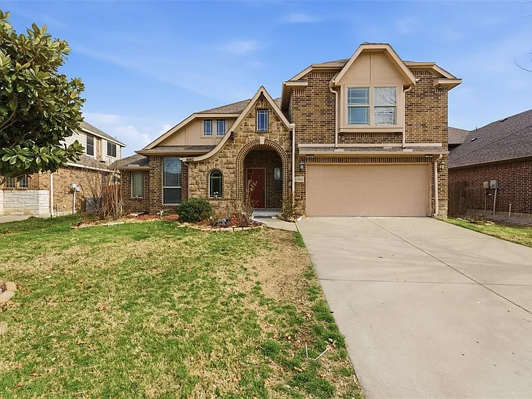 Tudor home featuring brick siding, an attached garage, concrete driveway, and a front yard