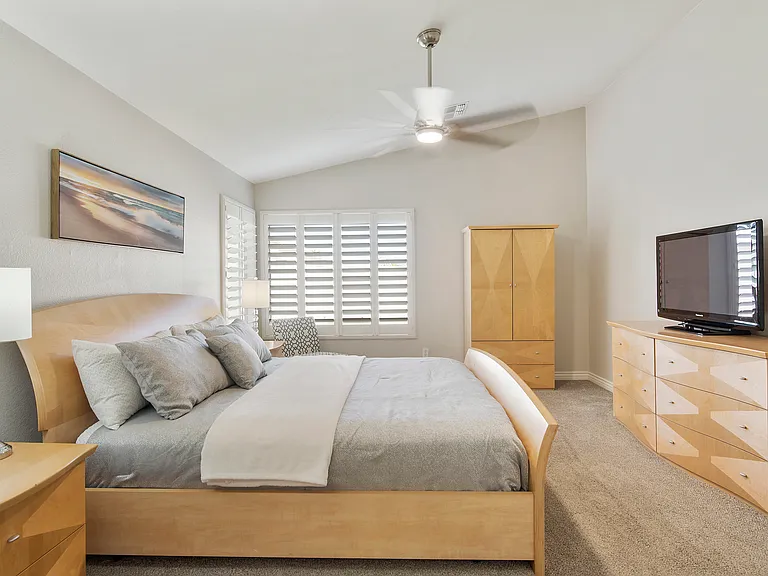 Primary bedroom with King size bed, 2 nightstands, armoire, dresser, fan, chair, tv and entrance to ensuite