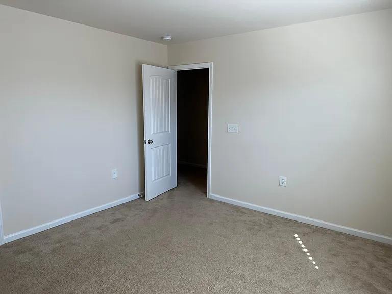A view from within bedroom 2 , taken from the corner opposite the closet. Immediately out the door and to the right is bathroom 2, to the left are the stairs and other rooms accessible via a hallway.