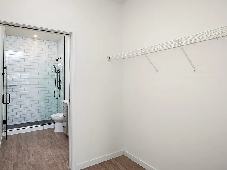 Modern bathroom with elegant subway tile shower and adjacent walk-in closet with ample shelving. Modern bathroom with elegant subway tile shower and adjacent walk-in closet with ample shelving.