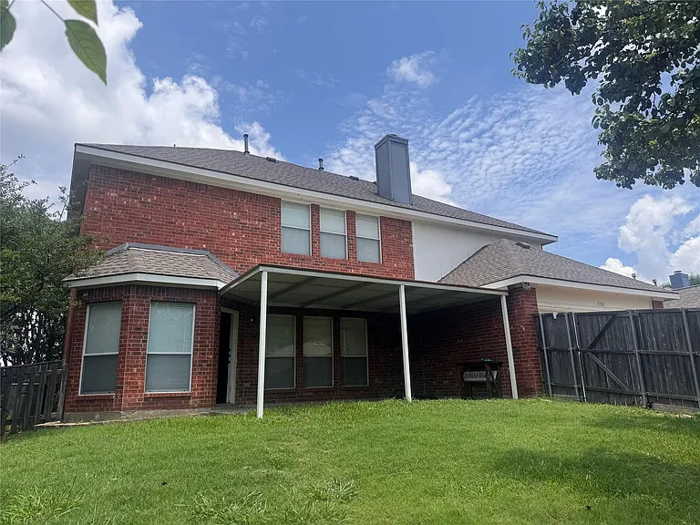 Brick exterior with a covered patio, fenced yard, and a bay window