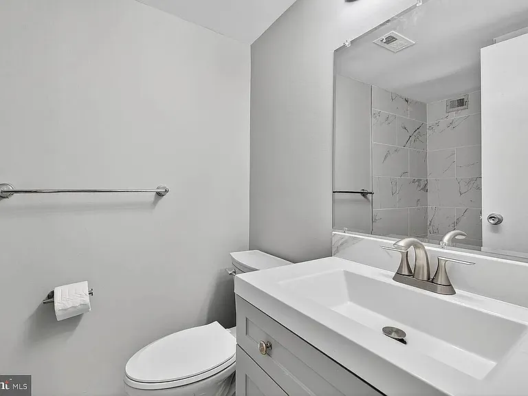 Clean bathroom with a wide vanity and single-basin sink, large mirror, and tile-surround tub/shower for easy upkeep.