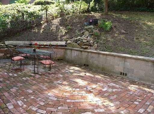 Side patio with waterfall, surrounded by wooded city property.