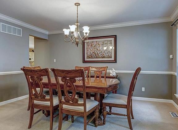 Dining room has elegant crown molding, chair railing and center chandelier.