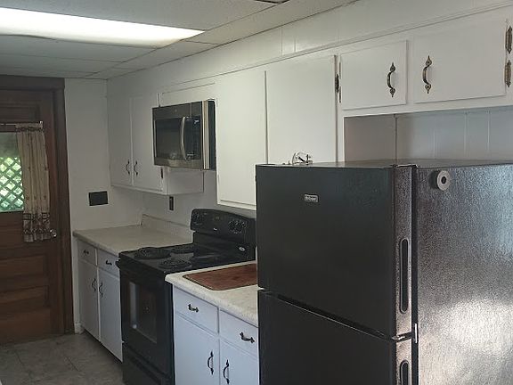 Kitchen with black appliances and full size microwave and refrigerator