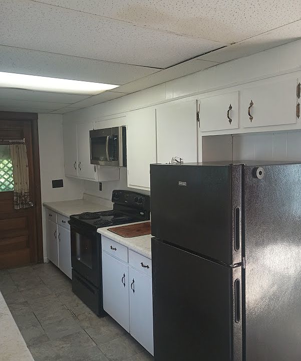 Kitchen with black appliances and full size microwave and refrigerator