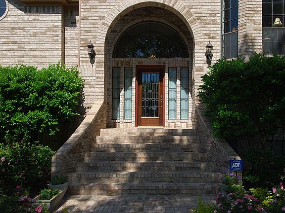 Grand entry with brick veneer portal and beautifully maintained grounds