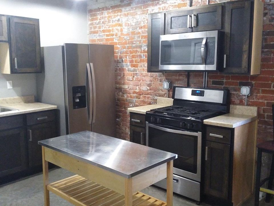Kitchen with stainless steel appliances and concrete flooring.