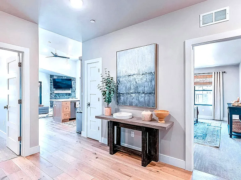 Open hallway connecting the main living areas, with a stylish console table and views into the living room and bedrooms