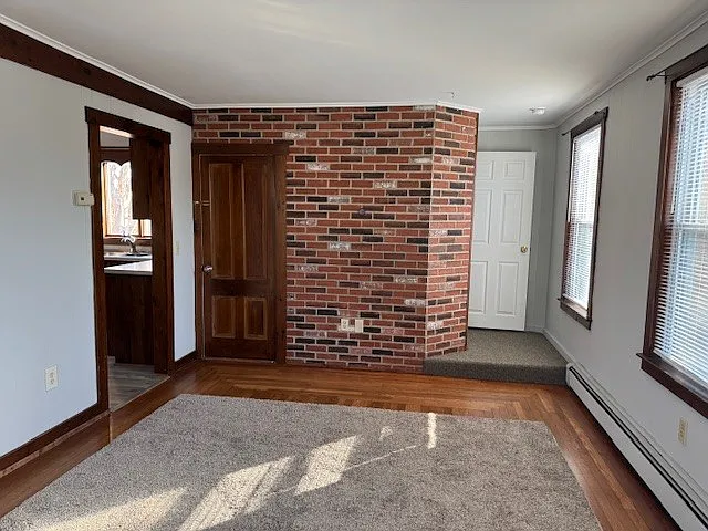 Staircase beside brick wall leads to 3rd level where 3 bedrooms are located