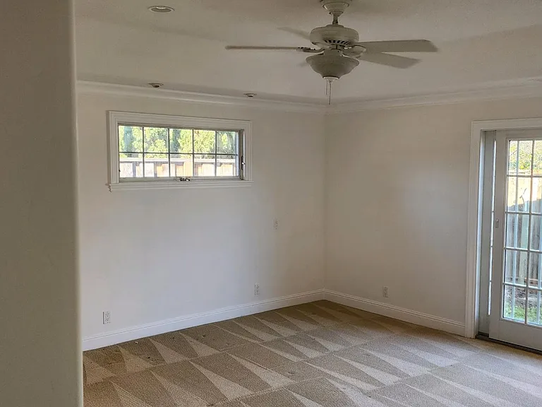 Primary bedroom with custom lighting, ceiling fan and sliding glass doors to backyard and hot tub.