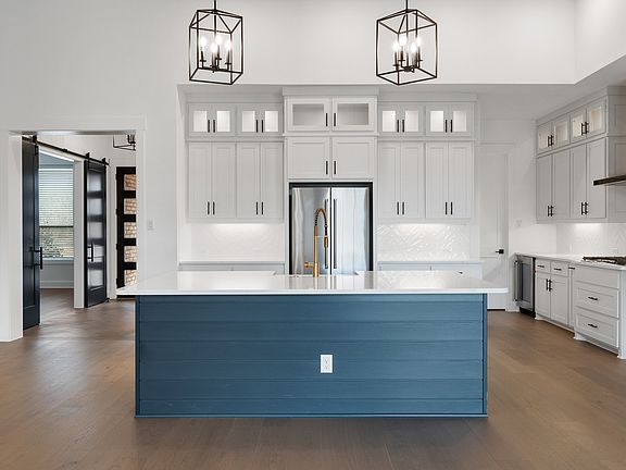 The kitchen has a beautiful blue island with quartz countertops.