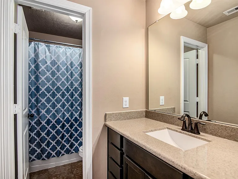 Full secondary bathroom with a spacious vanity and tub/shower combination.
