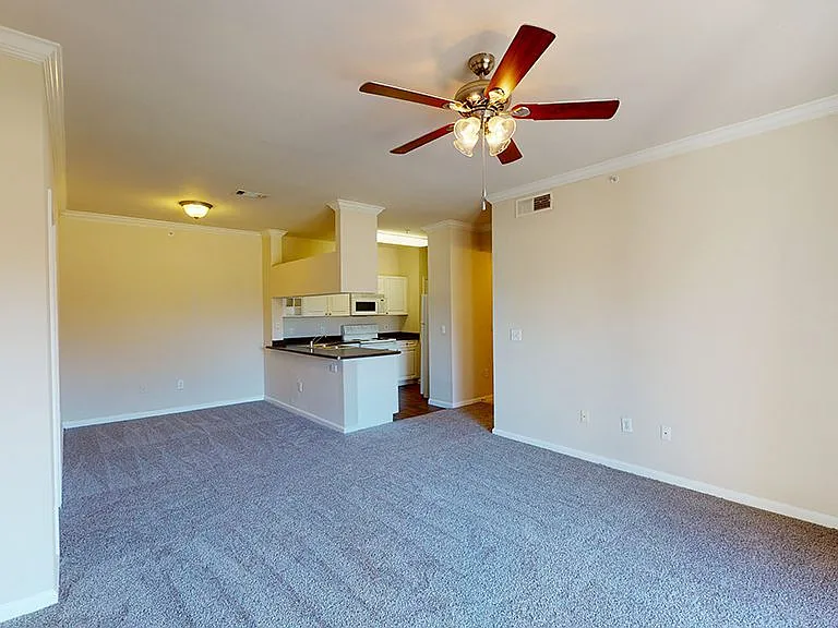 Apartment kitchen, dining and living room with plush carpet flooring.