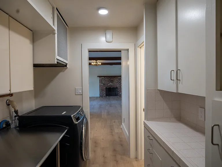 Across from the washing machine and dryer is more storage with countertop and MORE drawers and cabinets.