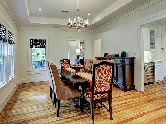 Formal dining room looks out to the front of the home. Custom roman shades, recent chandelier, wood flooring and coffered ceiling.