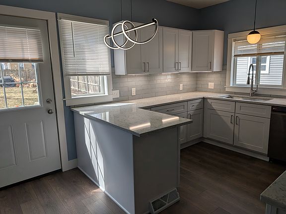 A dream kitchen in an apartment. New cabinets, quartz countertops, pendant lights, and under cabinet lighting.