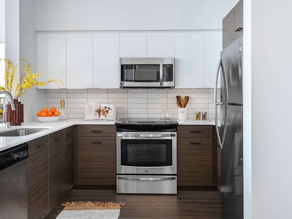 Apartment kitchen with stainless steel appliances, quartz countertops and wood-style flooring.