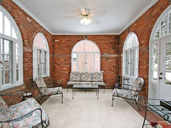 Relax on in the three season sunroom with arched brick work.