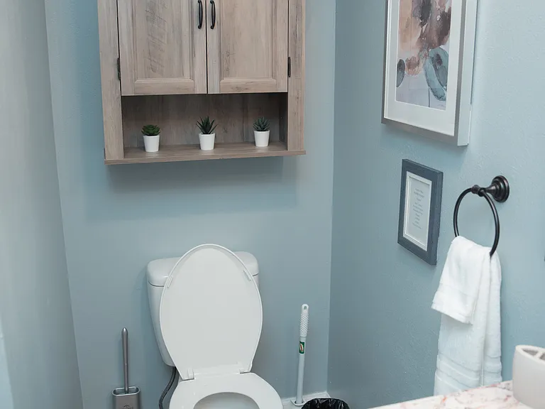 Clean and bright bathroom with a convenient wood-toned storage cabinet for all your essentials.