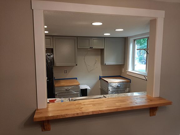 Looking into the new kitchen under construction! New cabinets, new butcher block counters next to the new stove, range hood, and refridgerator. New sink counter, cabinets, floor, and dishwasher!