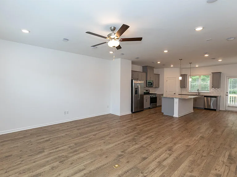 Spacious kitchen equipped with a refrigerator, sink, and ceiling fan.