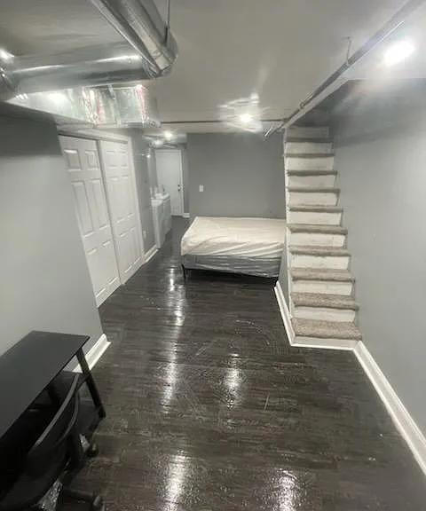 Open lower-level room with durable flooring, neutral walls, and convenient access to stairs and nearby storage.