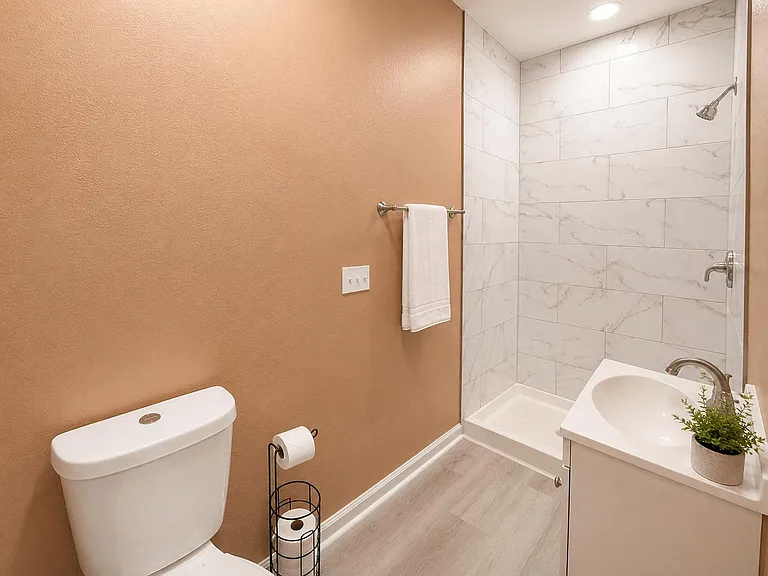 Full bathroom with tiled walk-in shower, single-sink vanity, and durable flooring for easy daily upkeep.