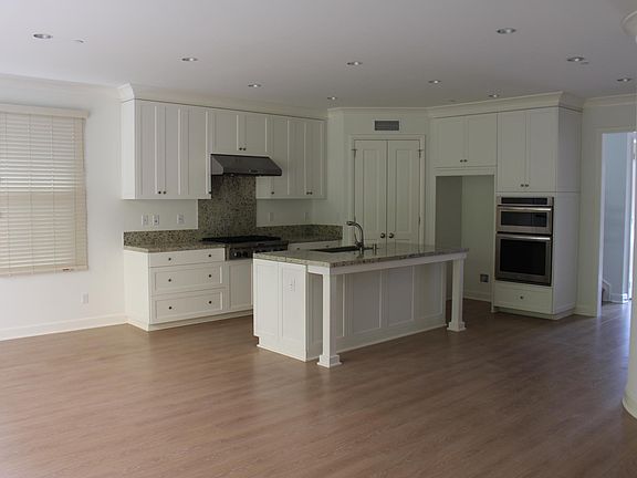 White, spacious kitchen with lots of storage and center island with room for seating.
