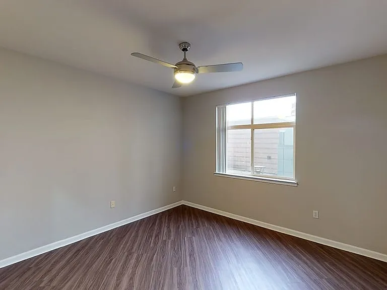 Spacious apartment bedroom with wood-style flooring.