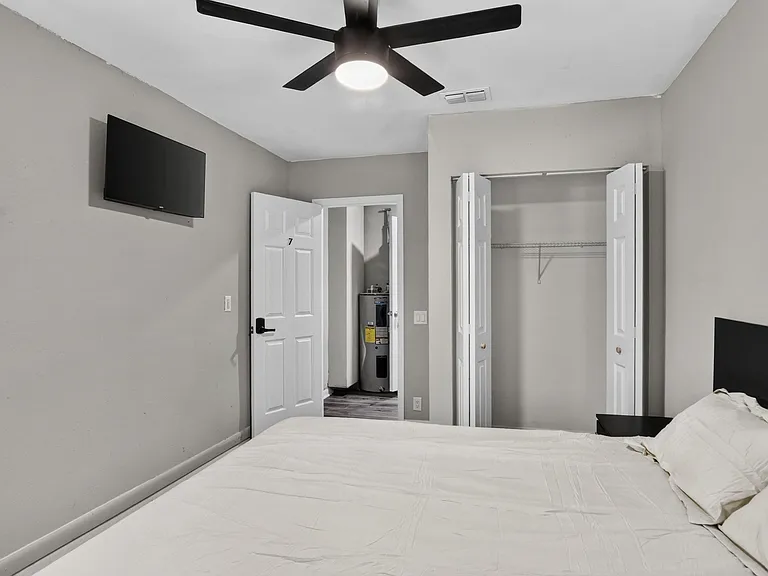 Bedroom with ceiling fan, wall-mounted TV, and a reach-in closet for convenient storage.