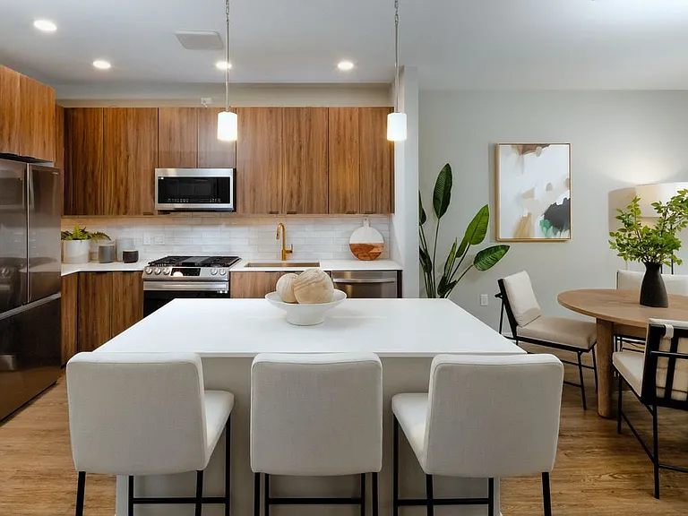 Upgraded Collection kitchen with stainless steel appliances, neutral quartz countertops, dark brown cabinetry, light grey backsplash, and hard surface flooring (model home)