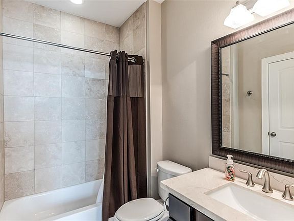 The private full bath to the first floor bedroom offers beautiful tile tub/shower, neutral counters and pretty fixtures.