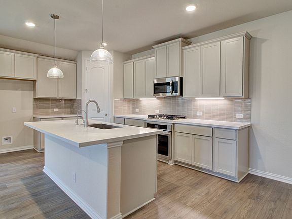 Kitchen featuring Pendant Lighting, Island, Under Cabinet Lighting, Ceramic Backsplash, Gas Cooking