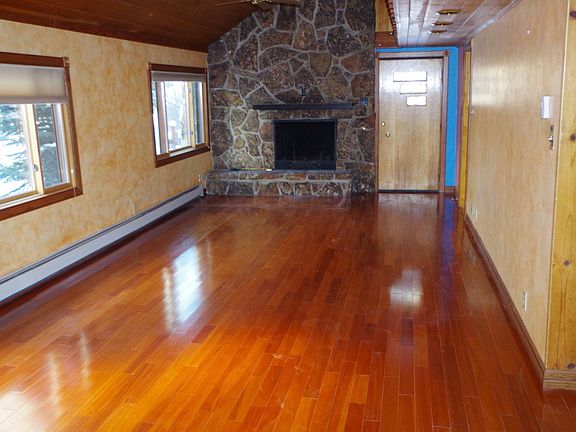 living room features vaulted ceilings, natural stone surround fireplace, hardwood floors and tons of sunlight
