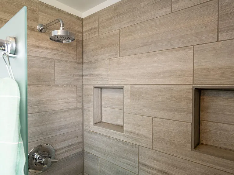 Primary bathroom shower with half-wall, integrated shelves, and thermostatic temperature control.